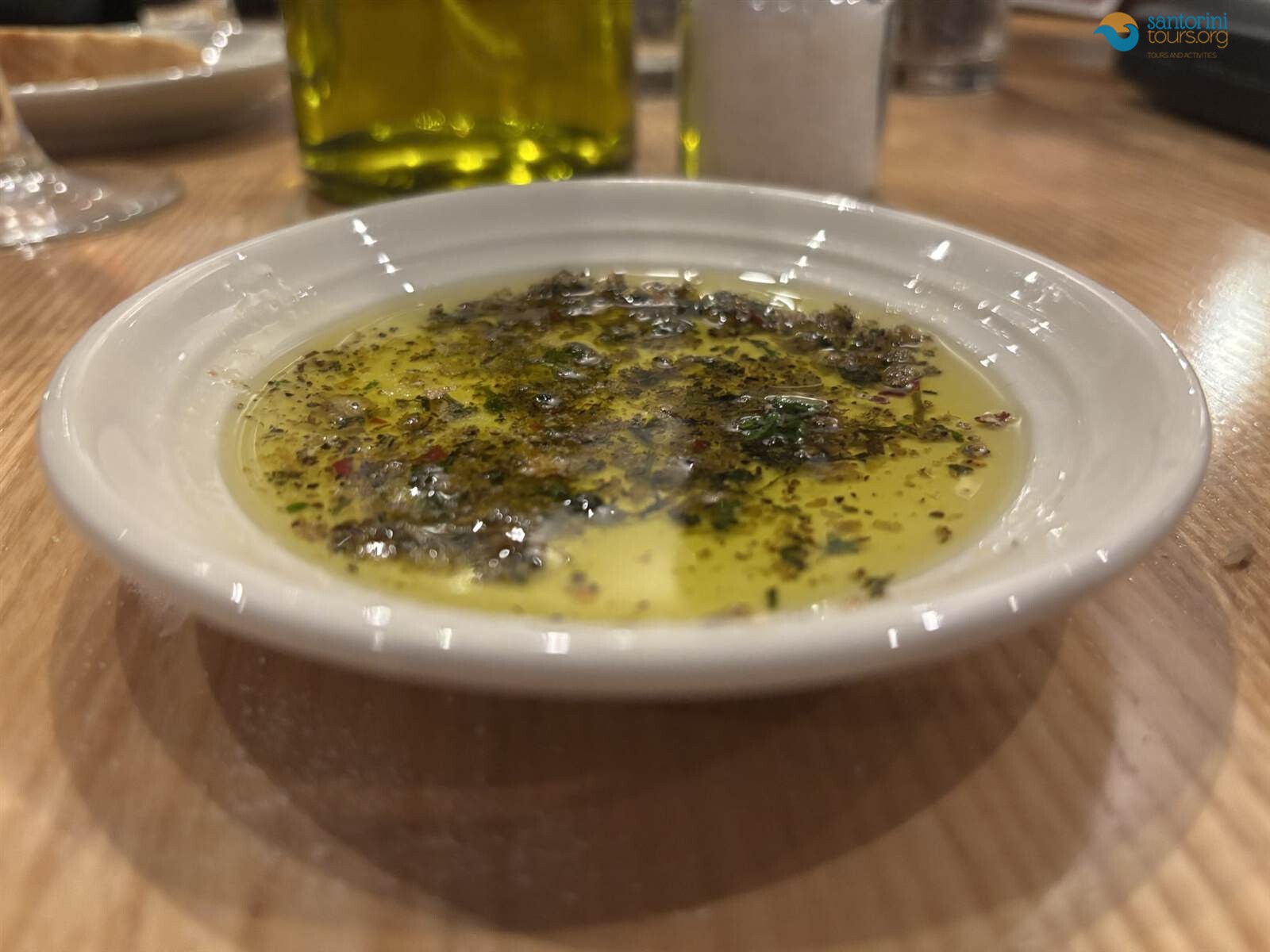 a dish of extra virgin oil and herbs at a santorini olive oil tasting